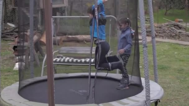 Ung pojke och flicka hoppar på studsmatta — Stockvideo