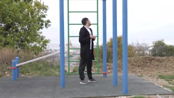 Kaukasisk ung man går in för sport på lekplatsen på en molnig dag — Stockvideo