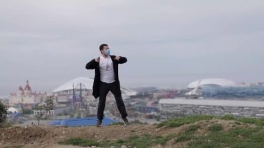 Genç maskeli adam Coronavirus Covid-19 'un arka planında dans ediyor.