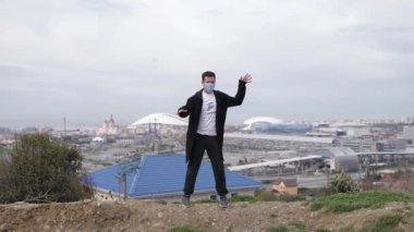 Genç maskeli adam Coronavirus Covid-19 'un arka planında dans ediyor.