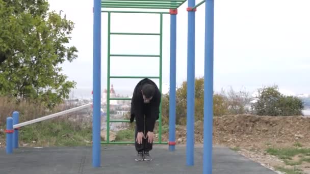 Caucasien jeune homme va dans pour le sport sur la cour de récréation par une journée nuageuse — Video