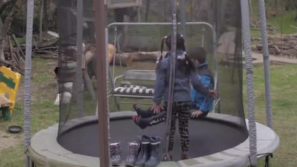Niño y niña saltando en el trampolín — Vídeo de stock