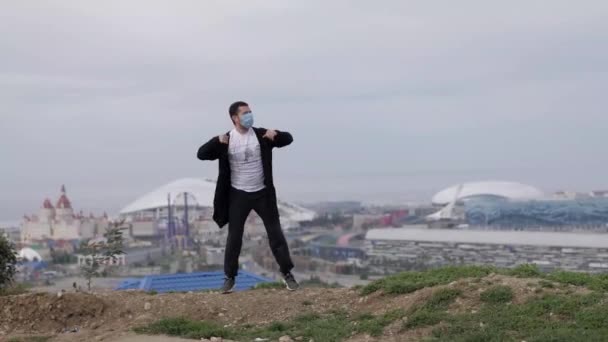 Młody zamaskowany facet tańczy na tle miasta koronawirus Covid-19 — Wideo stockowe