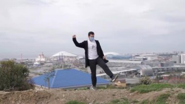 Genç maskeli adam Coronavirus Covid-19 'un arka planında dans ediyor.