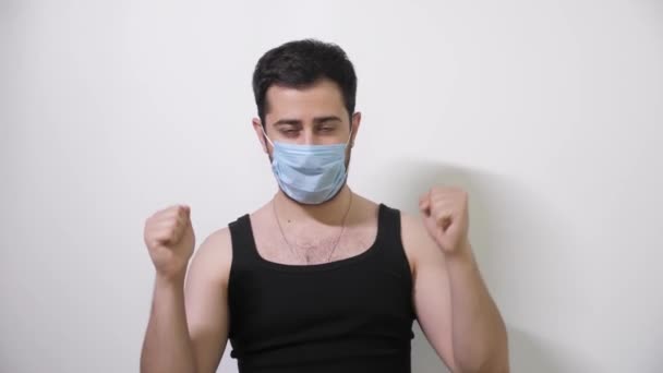 Caucasian man in medical mask makes an interesting move looks into camera Covid19 Coronavirus — Stock Video