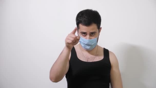 Homem caucasiano coloca sua máscara médica olha para a câmera e aponta para uma pessoa Covid19 Coronavirus — Vídeo de Stock