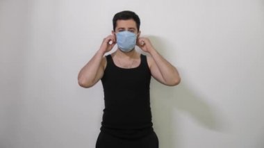 Beyaz adam siyah tişörtü virüsü korumak ya da yaymak için tıbbi maske takıyor. Beyaz arka plan kovid19 koronavirüs.