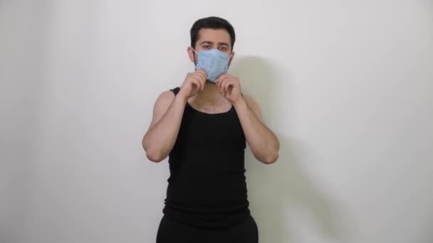 Young caucasian Man black t-shirt wears a medical mask for protecting or spreading virus, white background covid19 coronavirus — Stock Video