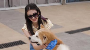 Kafkasyalı güzel bir kız tatlı bir akita köpeğinin kafasını okşuyor.
