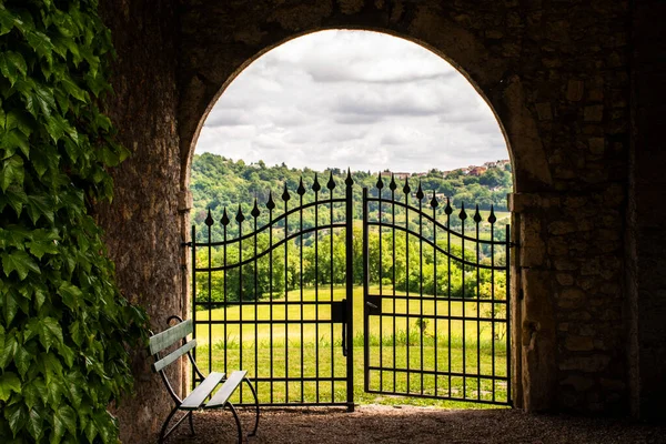 İtalya 'nın Vicenza kentindeki çayırları ve bahar ağaçları olan yeşil tepelerin manzarası yarı açık demir bir kapıdan görülüyor.