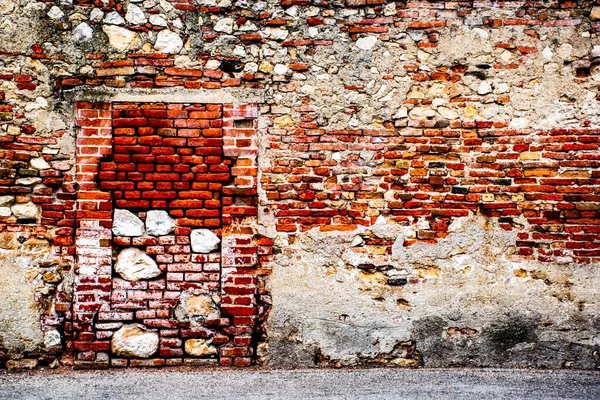 old wall with door closed by bricks and stones