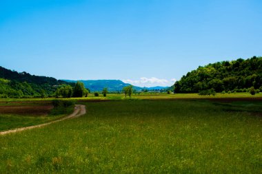 Tepelerde yeşil tarlalar ön planda gökyüzü ve arka planda düzlükler