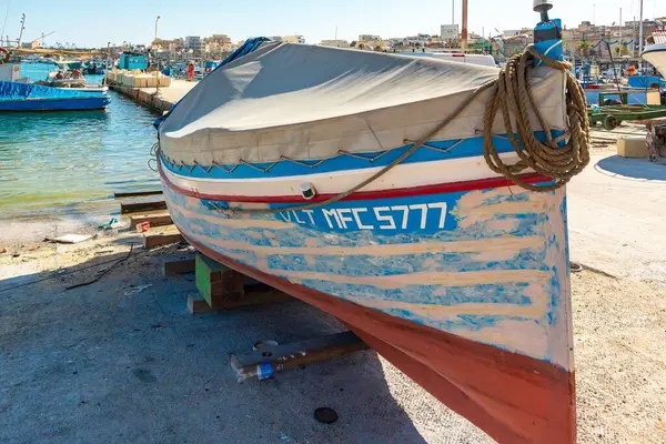 Marsaxlokk, Malta, Ağustos 2019. Tuval örtüsünün altında bir balıkçı teknesi kıyıya çekildi..