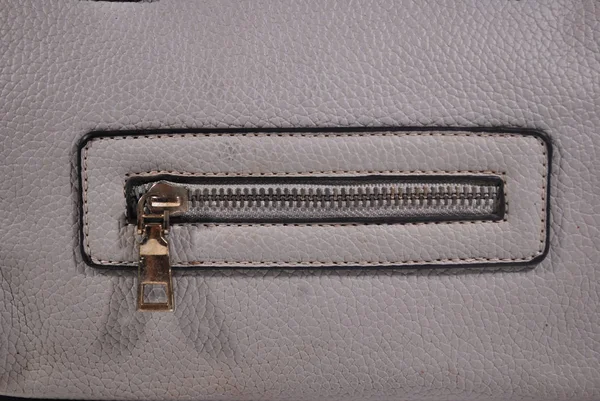 The zipper edge of the gray leather bag