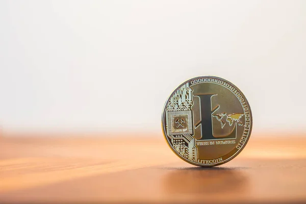 Cryptocurrency electronic money sign, focus on metal Litecoin stack on wooden table, blur white background copy space. Concept of decentralized, transfer or exchange digital money through blockchain.