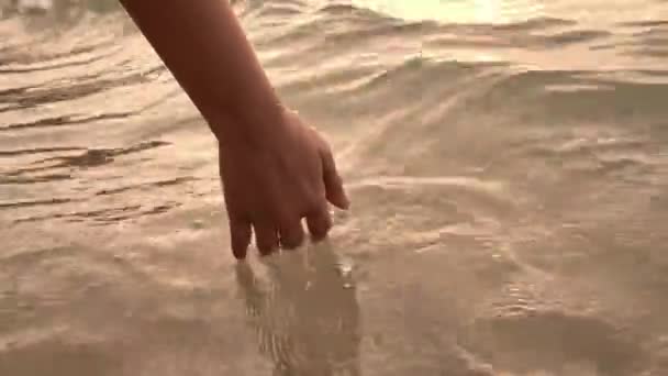 Cerca de la mano de la mujer tocando las olas de agua del mar . — Vídeos de Stock