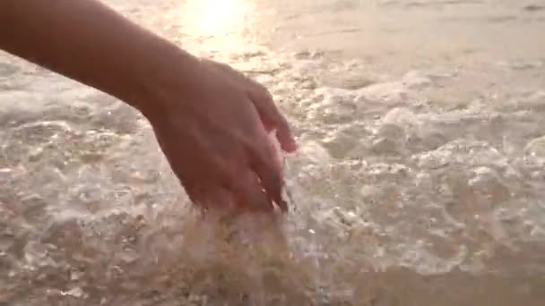 Mujer mano tocando burbujas brillantes de las olas del mar . — Vídeos de Stock