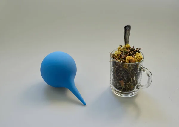 Tisane sèche de différentes herbes forestières dans une tasse en verre et une seringue bleue sur un fond isolé. petite cuillère. serviette — Photo