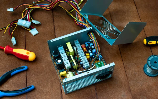 disassembled desktop PC power supply with desktop repair tools.