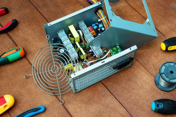 disassembled desktop PC power supply with desktop repair tools.