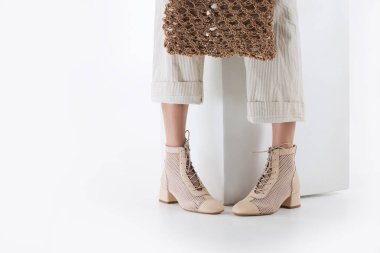 Şık ayakkabılı kadın bacakları, beyaz arka planda zarafet ve kadınlık.