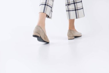 Şık ayakkabılı kadın bacakları, beyaz arka planda zarafet ve kadınlık.