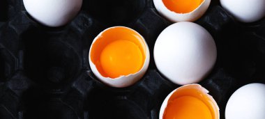 Kırık tavuk yumurtaları siyah arka planda