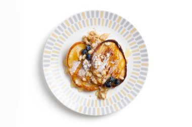 Krep, şeker, yaban mersini, ceviz, çam fıstığı ve bal ile izole edilmiş bir tabakta..