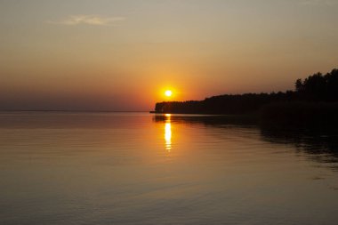 Nehir ya da denizin üzerinde altın günbatımının yatay fotoğrafı. Sudaki yansıma ateş gibi. Deniz Sıcaklığı.