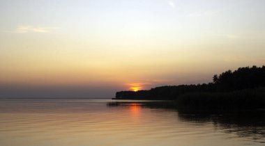 Nehir ya da denizin üzerinde altın günbatımının yatay fotoğrafı. Sudaki yansıma ateş gibi. Deniz Sıcaklığı.
