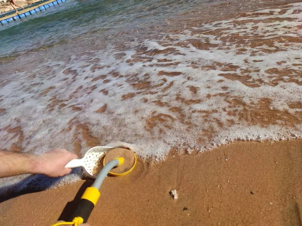 The photo of an underwater metal detector and a shovel on the sand.Treasure searching and tourist adventure background.