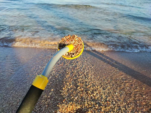 The photo of an underwater metal detector and a shovel on the sand.Treasure searching and tourist adventure background.