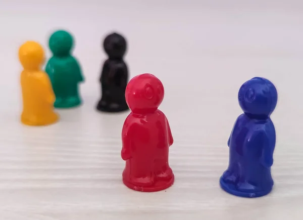 Conception  - partnership, cooperation, game figures or pawns in a business situation. Colored chips of tabletop game in the little men form