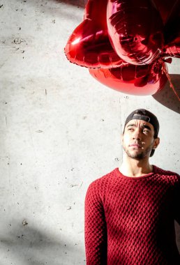 Sevgililer gününde kalp şeklinde balonları olan bir adam. Kırmızı ceketli adam.