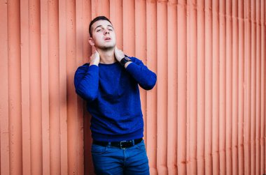 Arka planda mavi kazaklı dalgın bir gencin portresi.