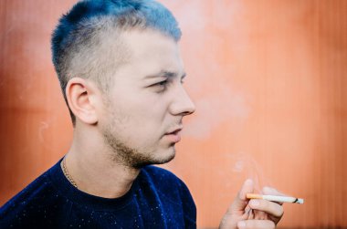 Duvarın yanında sigara içen bir gencin portresi.