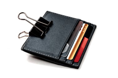 Beyaz arka planda kredi kartı olan deri kart sahibi. Kart sahibi ataçla tutturulmuş. Elektronik cüzdanın sembolü.