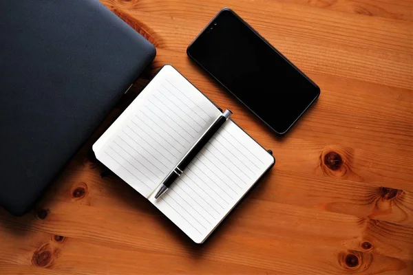 Portátil, portátil, pluma y teléfono móvil en una mesa de madera. Parte superior ve — Foto de Stock