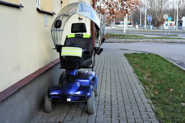 blue four wheeled mobility scooter- electric wheelchair parked o
