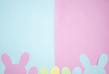 Paskalya yumurtaları ve tavşan kulakları kağıttan yapılır. Pastel pembe ve mavi tonlarda kompozisyon. Yukarıdan bakıldığında, düz katman, kopyalanacak yer