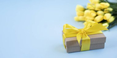 Bir buket sarı lale ve mavi arka planda bir hediye. Ulusal Doktorların Günü. Hemşire günün kutlu olsun. Sağlık günü. Üst görünüm, boşluğun kopyası.