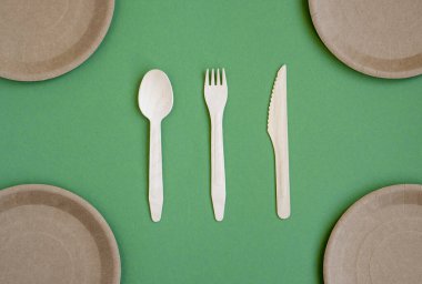 Yiyecek, ahşap ECO bıçağı, çatal, çatal ve fotokopi alanı olan yeşil bir arka plan için çevre dostu sofra takımı. Çevre gıda ambalajı geri dönüşümlü Kraft kağıdından yapılır. Çevre dostu piknik yemekleri. Seçici odak.