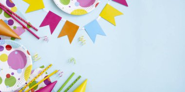 Tatil için kağıt masa takımı. Mavi bir arka planda doğum günü partisi dekorasyonu. Renkli plakalı çerçeve ya da arkaplan, karnaval şapkası ve flamalı. Çevre dostu gıda ürünleri.