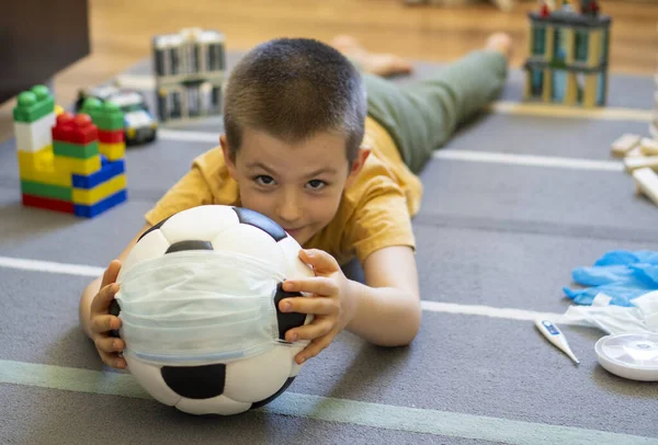 Soccer ball in a medical mask. Activities at home with your children during home coronavirus quarantine.Sports at home. Stay at home