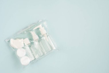 Plastik kaplar. Mavi arka planda seyahat ayarlandı. Krem, şampuan, lens kapları ve kapalı bir çantada diş ipi için plastik şişeler. Üst görünüm, boşluk kopyala