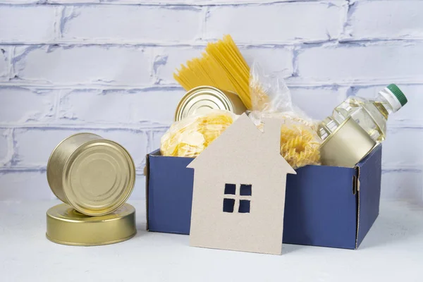 Food donations. Secure contactless delivery service during quarantine. Stay at home, shop online during a coronavirus outbreak.Various canned food, pasta and cereals, corn flakes in a cardboard box.