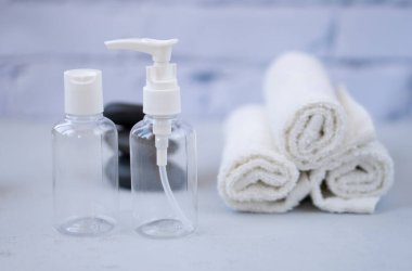 Plastik kaplar. Spa kompozisyonu, eğlence ve konukseverlik. Güzellik ve cilt bakımı. Plastik şişeler, lens kapları ve arka planda beyaz havlular.