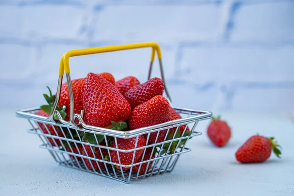 fresh strawberries with a shopping basket on a light background. advertising concept for fresh products.Self-service supermarket shopping basket with fresh strawberries. copy space