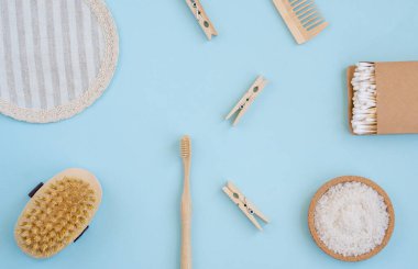 Açık mavi arka planda yıkanmak için sıfır atık. Doğal sisal fırça, ahşap tarak, deniz tuzu, bambu diş fırçası, bez ve pamuk tomurcukları. Üst manzara, düz uzanma, 