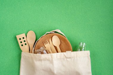 Sıfır Atık Pamuk Torbası. Sıfır atık. Tekstil eko çantası, cam kavanozlar, yeşil arka planda ahşap mutfak aksesuarları. Çevre dostu ve konsepti yeniden kullan. Üst manzara, düz uzanma. 